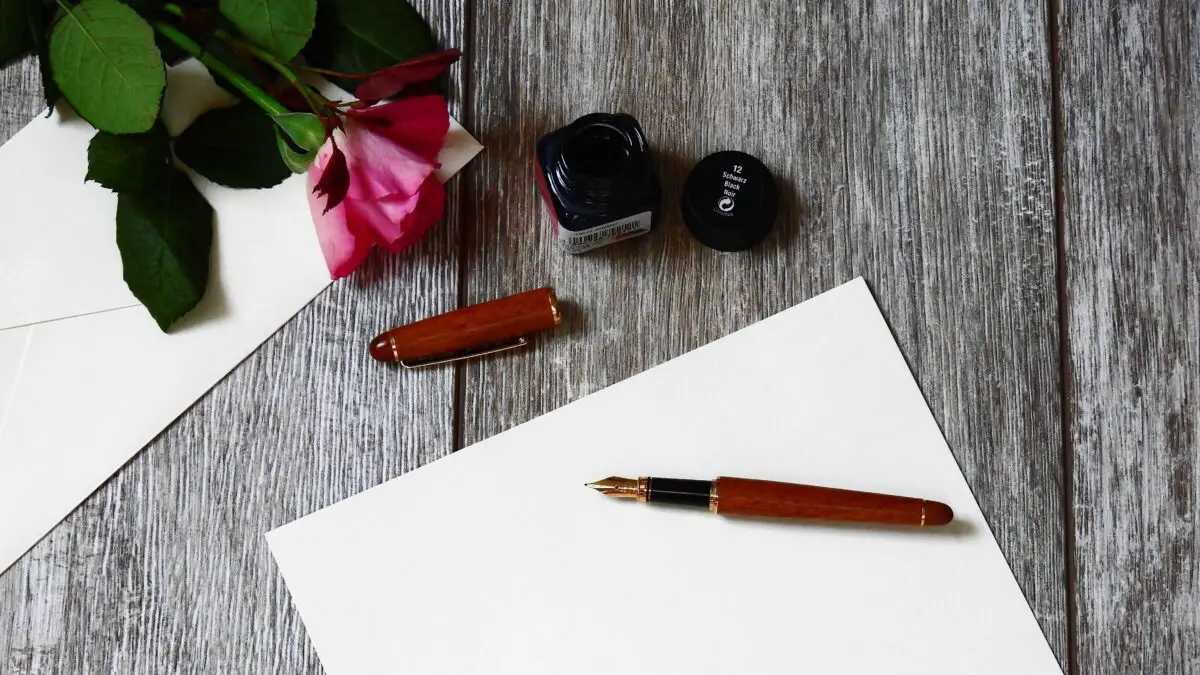 Writing idioms - an overhead, close up of a pen, paper, ink pot and flowers