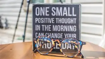 Positive idioms - a sign with a positive message and sunglasses on a table