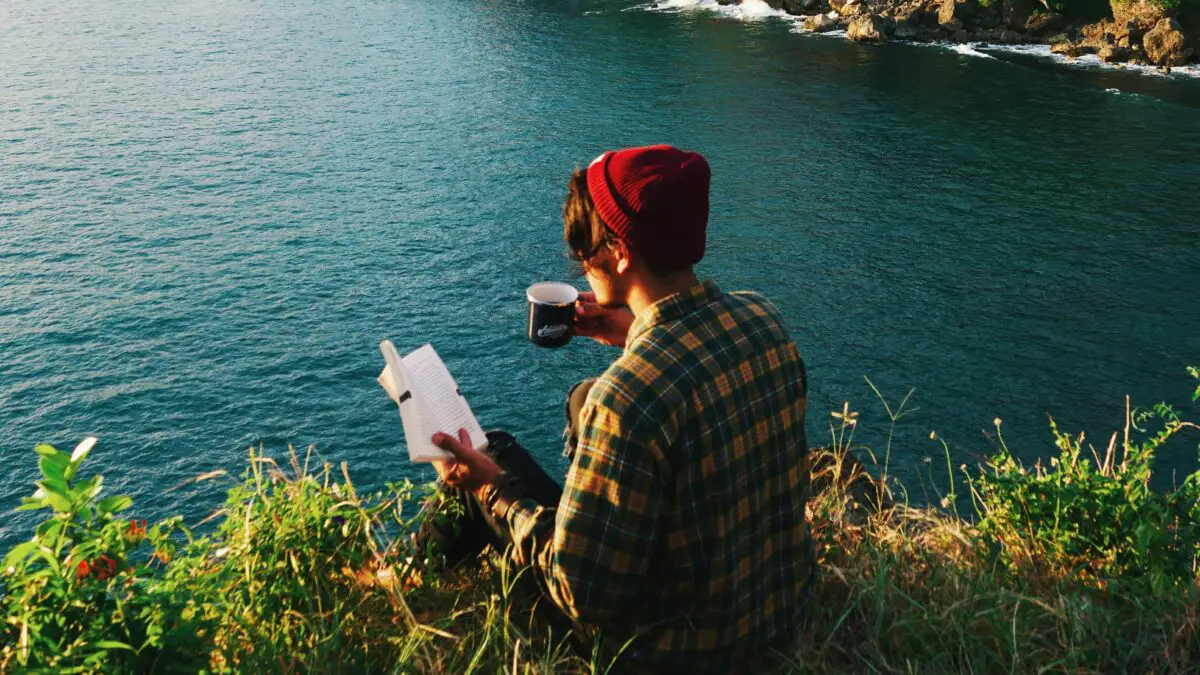 Reading idioms - the back a man reading a book on the edge of a lake