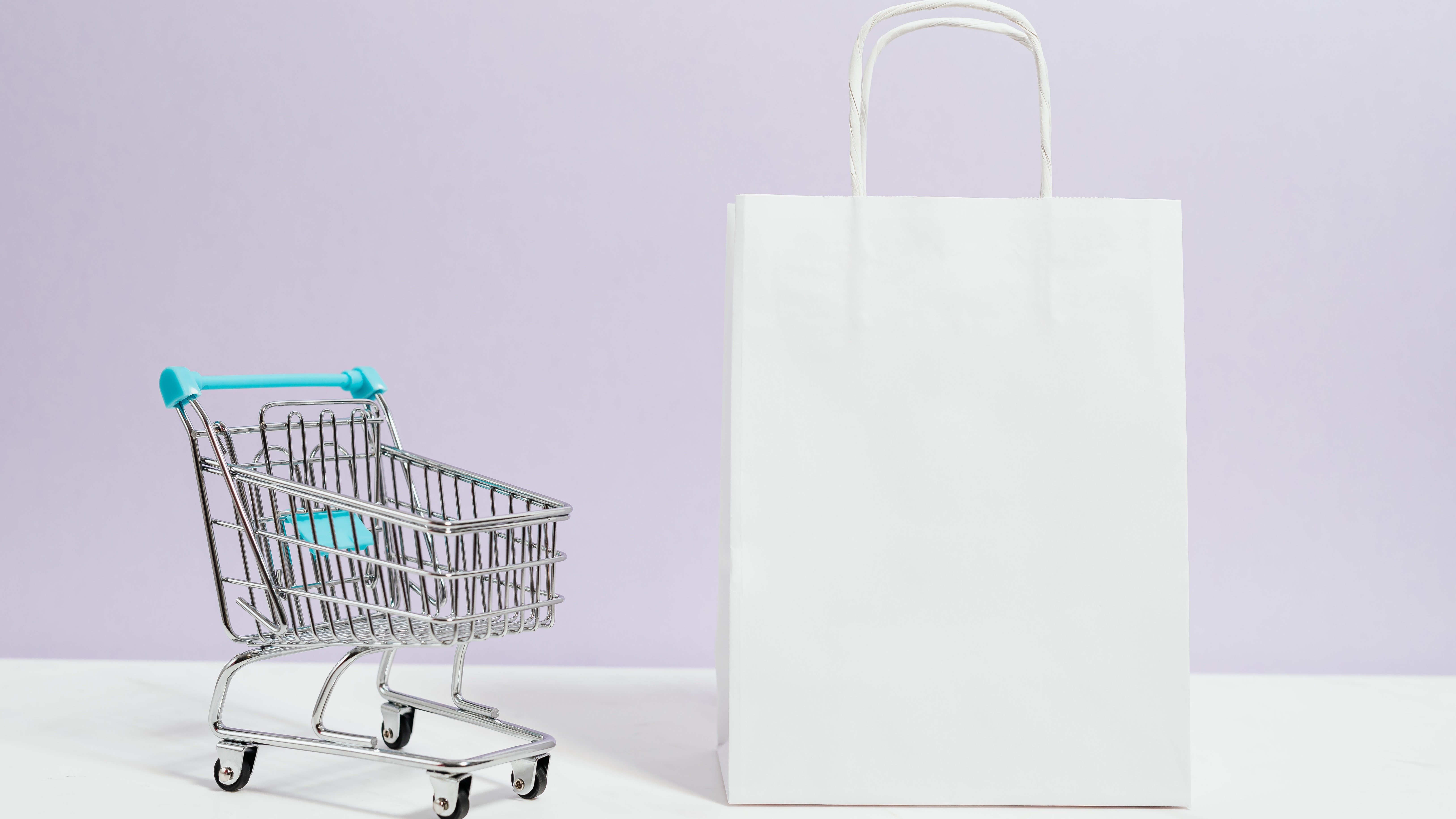 Shopping idioms - a close of up a small shopping trolly next to a white paper bag