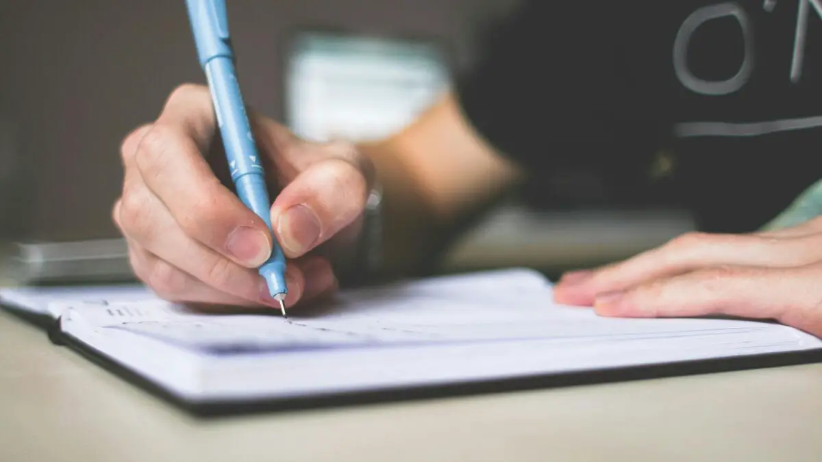 person writing down their smart goals for learning English